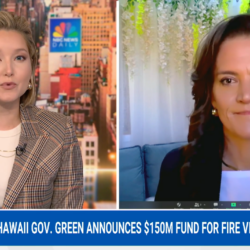 Two women speak on a news broadcast about Hawaii’s $150M fund for fire victims, with cityscape background.